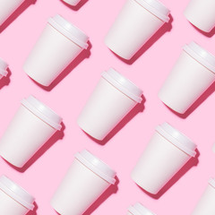 Pattern of disposable coffee cups on a pink background. Flat lay.