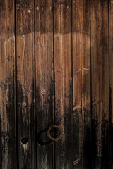 Obraz premium Spanish wooden door with dark and orange woods and a wrought metal horseshoe handle