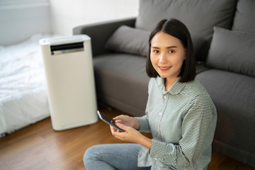 Air purifier , Asian Business woman working with laptop use phone  with filter for clean room in a...