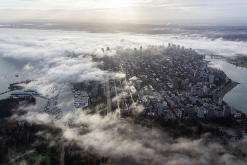 Downtown Vancouver, British Columbia, Canada. Aerial View of a modern city on the West Coast of Pacific Ocean during a cloudy sunrise and covered in Fog.
