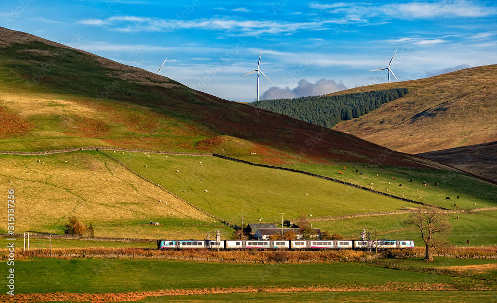 Wall mural beautiful Landscape ,train A pair of Scotrail passenger trains climbon scottish highlands scenery of mountains and wind turbine on a summer's day