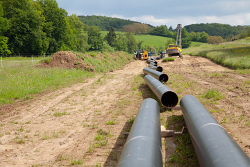 Various unplugged gas pipes lead in an idyllic landscape to the background with equippment to pipe...