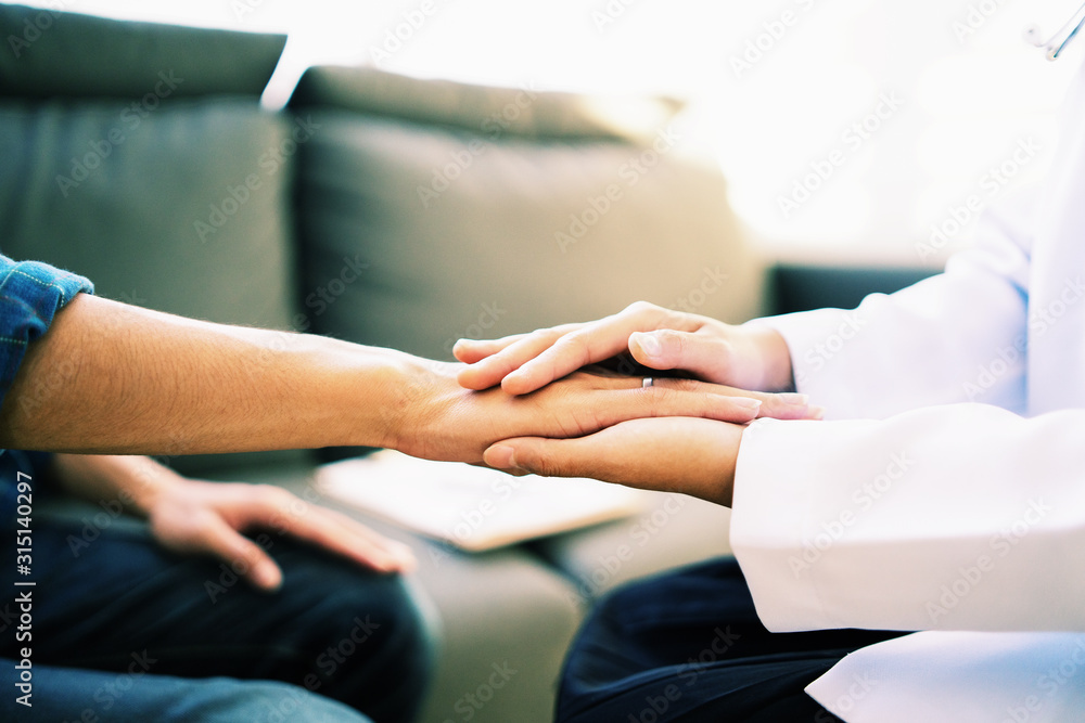 Wall mural doctor and patient shaking hands in office, they are sitting at desk, discussing something ,having c