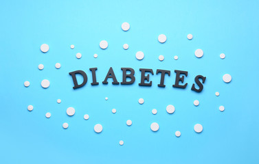 Word DIABETES and pills on color background