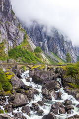 rocks in a rushing mountain river during a rainy day in Norway