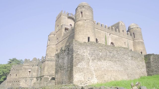 Camera tracking right at the base of the east facade of Fasilides Castle within the Fasil Ghebbi royal enclosure complex in Gondar, Ethiopia