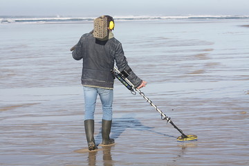 Mann mit Metallsuchgerät sucht bei Ebbe den Strand ab