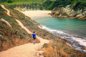 man descending along a dirt track by the cove of the tower of hercules in a coruna, spain