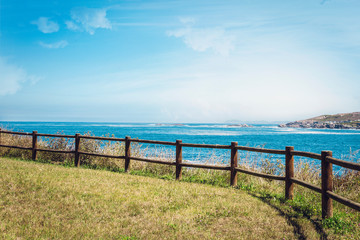 Obraz premium wooden fence at the top of the hill overlooking the sea in a coruna, spain