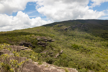 Fototapeta na wymiar Typical rock formation and sloping landscape in Minas Gerais in Brazil against a blue sky with clouds seen from a high plateau in the Andorinhas [swallows] park near Ouro Preto