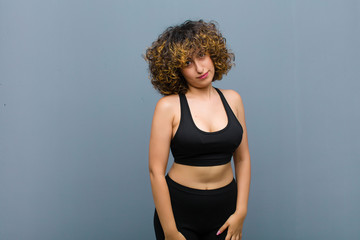 young sports woman looking proud, confident, cool, cheeky and arrogant, smiling, feeling successful...