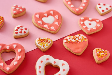 Decorated heart shape cookies on a colored red and pink background, top view