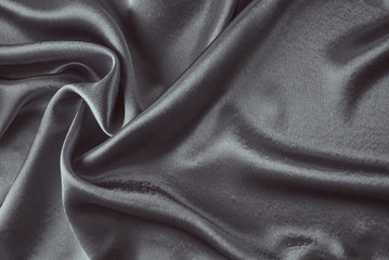 Dark silk background with a folds.  Abstract texture of rippled satin surface