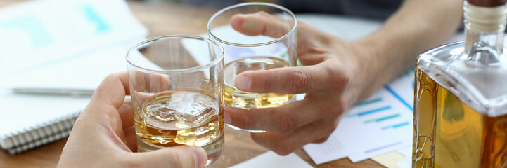 Focus on male hands holding glassful with whisky. Colleagues clinking glasses with alcoholic beverage. Business people celebrating signing profitable contract