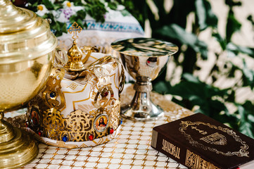 Fototapeta na wymiar Wedding crowns in church ready for marriage ceremony. close up. Bible, crown, bowl on table