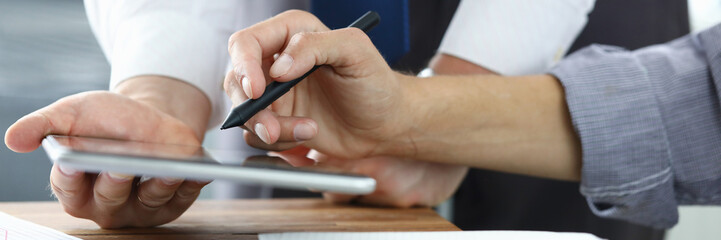 Focus on colleagues hands holding modern tablet and stylos. Businessmen discussion new biz project....