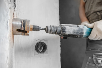 Builder worker pneumatic hammer drills hole in concrete brick wall with diamond crown for electric...