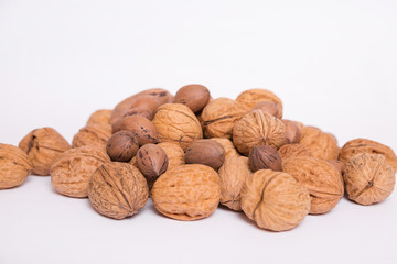 Nueces y nueces de pecán recolectadas sobre fondo blanco.