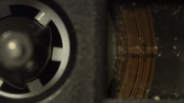 Macro shot of audio cassette reel with a magnetic tape rotating in the tape recorder during the playback. Concept of playing music, recording a conversation, listening sounds. 4K resolution video.