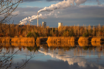 Coal power plant near Czech city Melnik with smoking chimneys mirroring in water of lake