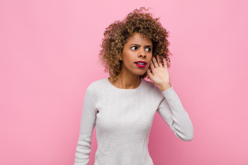 young african american woman looking serious and curious, listening, trying to hear a secret...