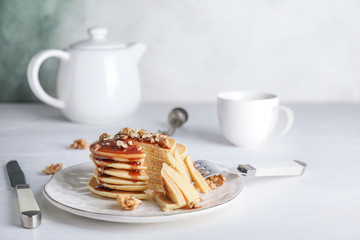 Plate with stack of tasty pancakes on table