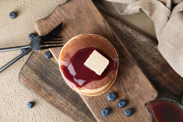Board with stack of tasty pancakes on table