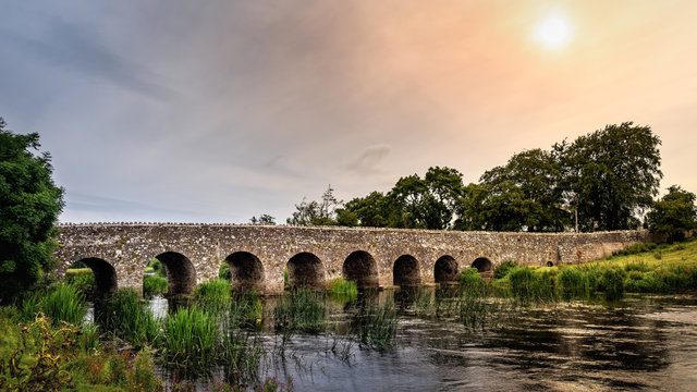 Old 12th century stone arch bridge over a river. Count Meath, Ireland