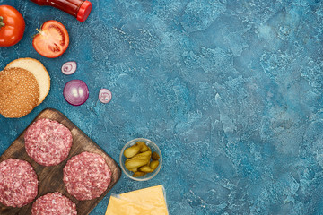 top view of fresh burger ingredients on blue textured surface with copy space