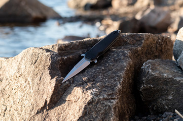 Knife on a background of stone and river. Knife dagger on the stone.