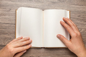 A5 open book mockup with hands. Empty template of page. Blank for design. On wooden background.
