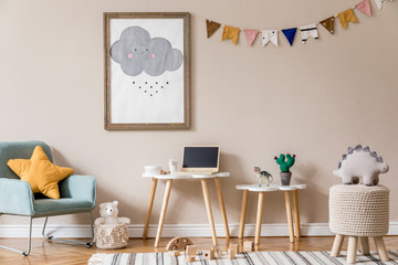 Stylish and beige scandinavian decor of kid room with mock up poster frame, design furnitures, natural toys, hanging colorful flags, plush animal and child accessories and teddy bears. Home decor.