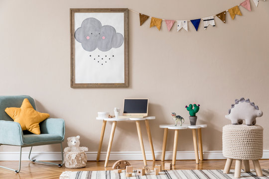 Stylish and beige scandinavian decor of kid room with mock up poster frame, design furnitures, natural toys, hanging colorful flags, plush animal and child accessories and teddy bears. Home decor.