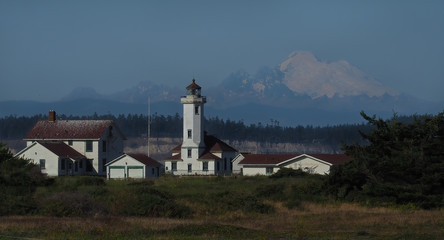 Fototapeta na wymiar Fort Worden lighthouse and outbuildings at Port Townsend, Washington with Mount Baker and Cascade Mountains in background