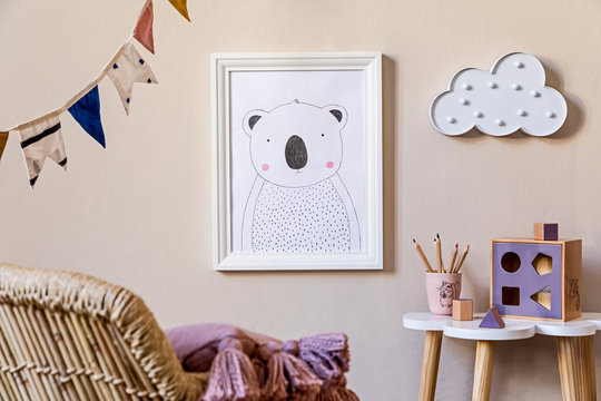 Stylish scandinavian nursery interior with mock up photo frame, wooden toys, design furniture, pillows and accessories. Beautiful decoration on the beige background wall. Home decor for children room.