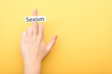 cropped view of man showing middle finger with card sexism isolated on yellow