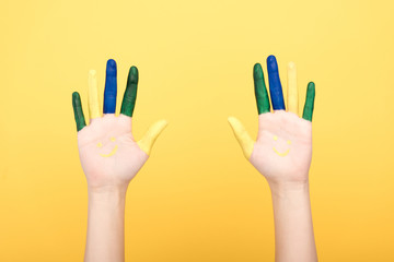 cropped view of woman with colorful fingers showing palms on yellow background