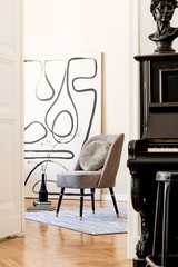 Interior design of living room with stylish gray armchair, abstract paintings, flowers in vase, pillow, plaid, black piano and elegant personal accessories. Beige concept Modern home staging. Template