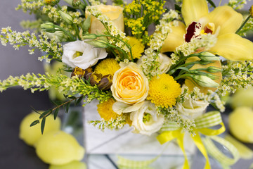 composition of fresh flowers in yellow colors (rose, orchid, eustoma) in a gift box in the form of an envelope on a gray background © ABeliayeu