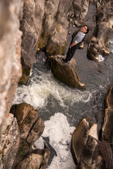 Young man posing in the field and with a bridge in the background. Enjoying the outdoors