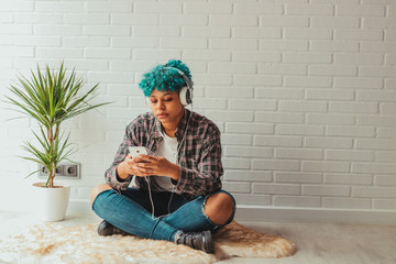 happy young woman or girl listening to music at home or apartment with mobile phone and headphones
