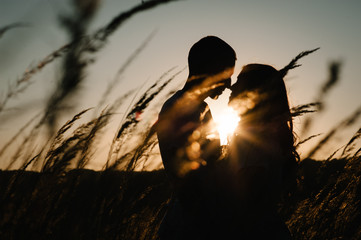 Young couple hugging and kissing, at sunset in autumn at an outdoor on park. at the field grass on...