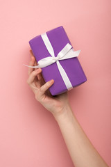 cropped view of woman holding gift on pink background