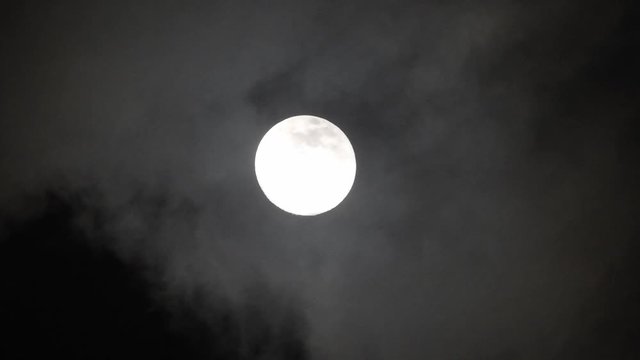 Clouds passing by moon at night. Full moon at night with clouds in real time.
