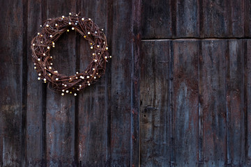 Advent wreath  with little light bulbs hanging on an old rough wooden door