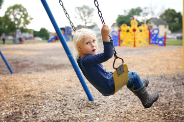 Cute Little Preschool Child Swinging at Playground