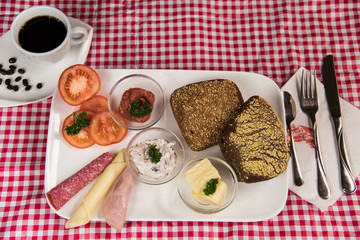 on a red chequered tablecloth is a plate with a hearty breakfast and a cup of black coffee