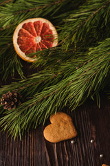Gingerbread cookies in heart shape, powdered sugar on wooden background, citrus dried grapefruit, fir tree branch, angle view, selective focus