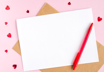 Minimalistic card mockup with envelope, postcard, pen, red hearts on pink background. Flat lay, top view, copy space. Valentines day concept.