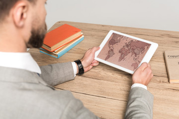 partial view of businessman using digital tablet with world map on screen isolated on grey